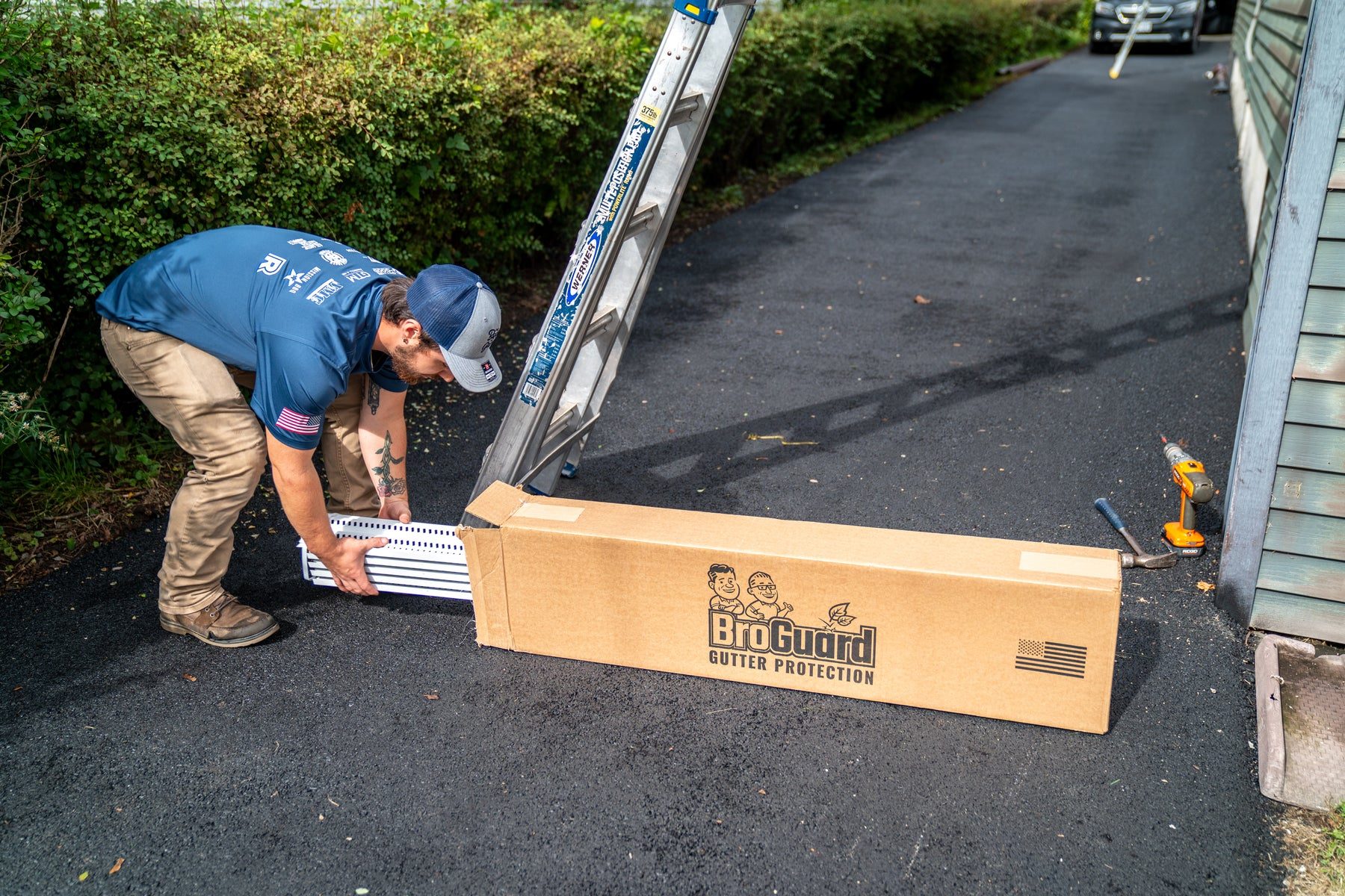 Installer unboxing BroGuard micro-mesh gutter guard panels on a driveway