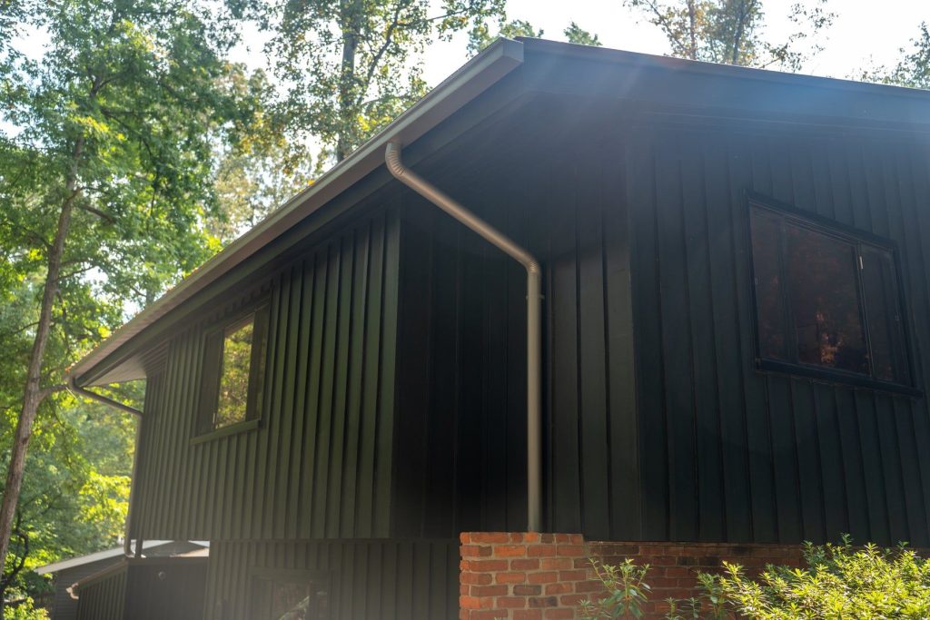 Dark box gutter and downspout on a board and batten building