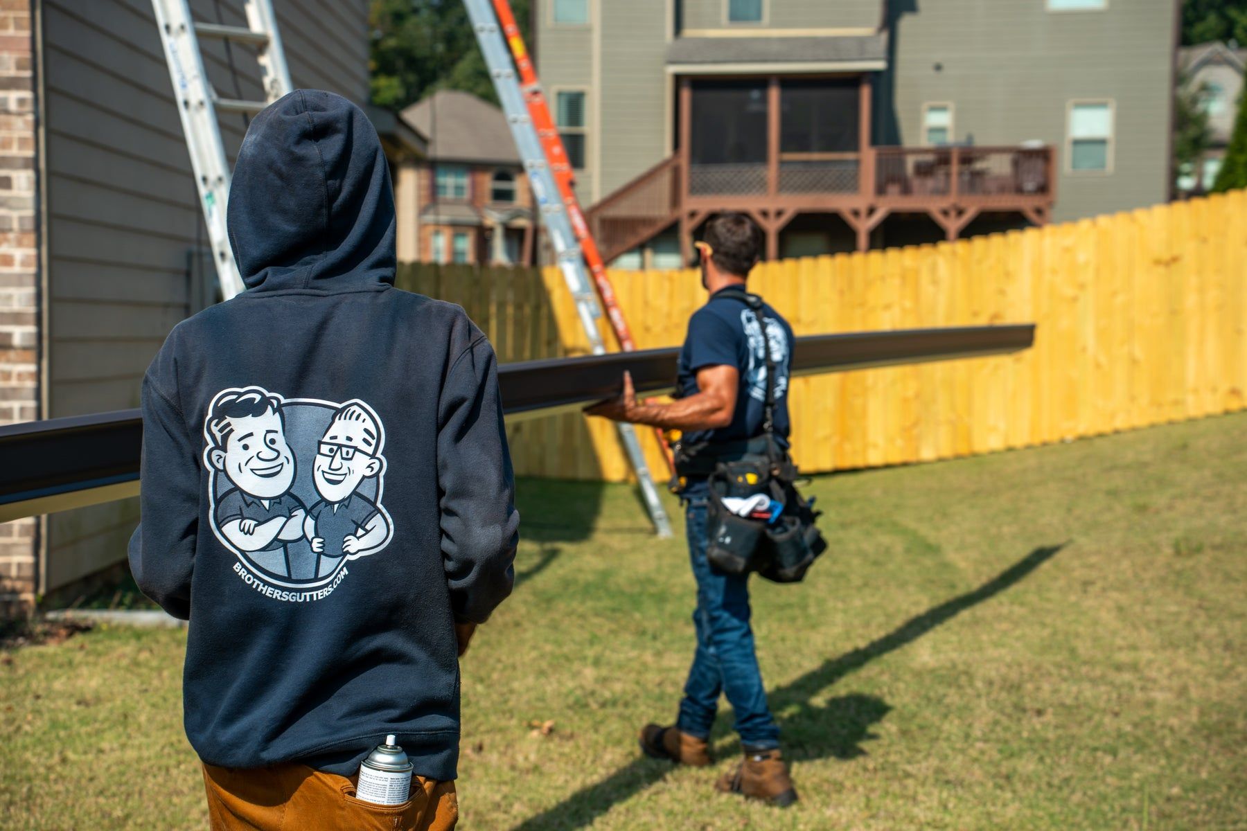 Crew carrying a gutter across the yard