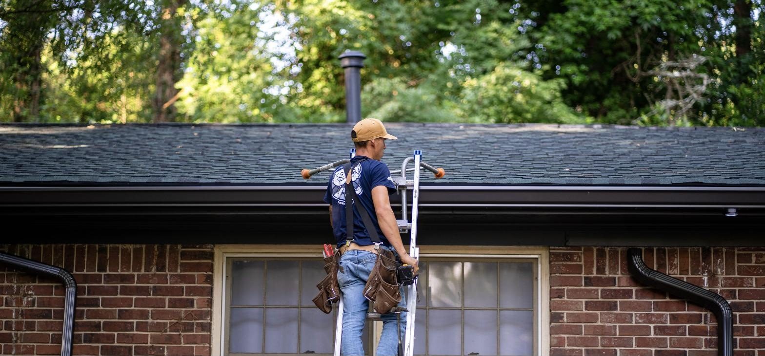 Installer at the roofline of a brick ranch home