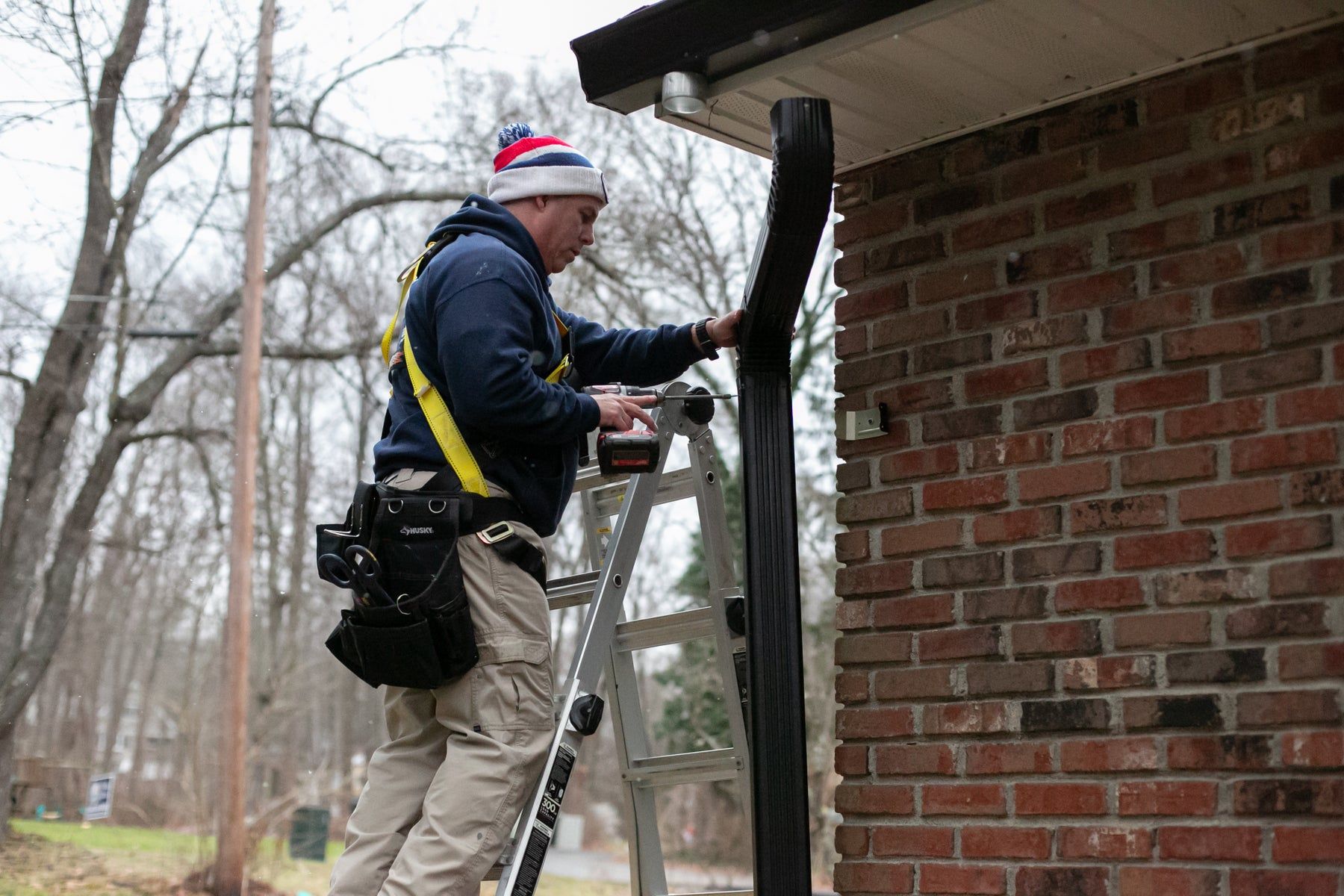 Installer fitting a downspout on a brick home